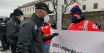 Policajti pri záchranárovi s transparentom pred NR SR.