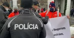 Policajt záchranárovi nariaďuje schovať transparent.