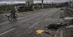 Dievča jazdí na bicykli vedľa mŕtveho tela ruského vojaka v meste Buča pri Kyjeve.